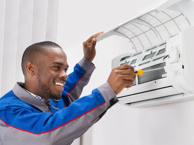Un technicien ouvre le panneau d'une unité intérieure de climatiseur pour en nettoyer les filtres